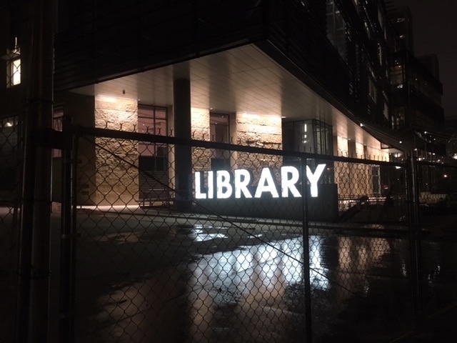 Austin Central Library sign lit up in early morning.